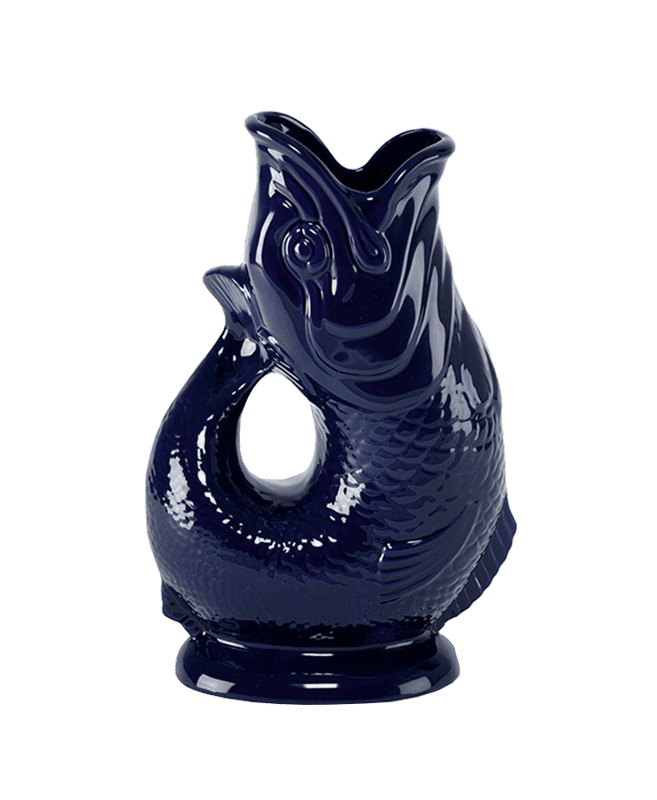 Die Gluckigluck Karaffe X-Large Kobalt Blau von Gluckigluck ist eine glänzende, dunkelblaue Keramikkanne in Fischform mit strukturierten Schuppen, die aufrecht auf einem runden Sockel steht und für ihr charmantes Gluckern beim Eingießen bekannt ist.
