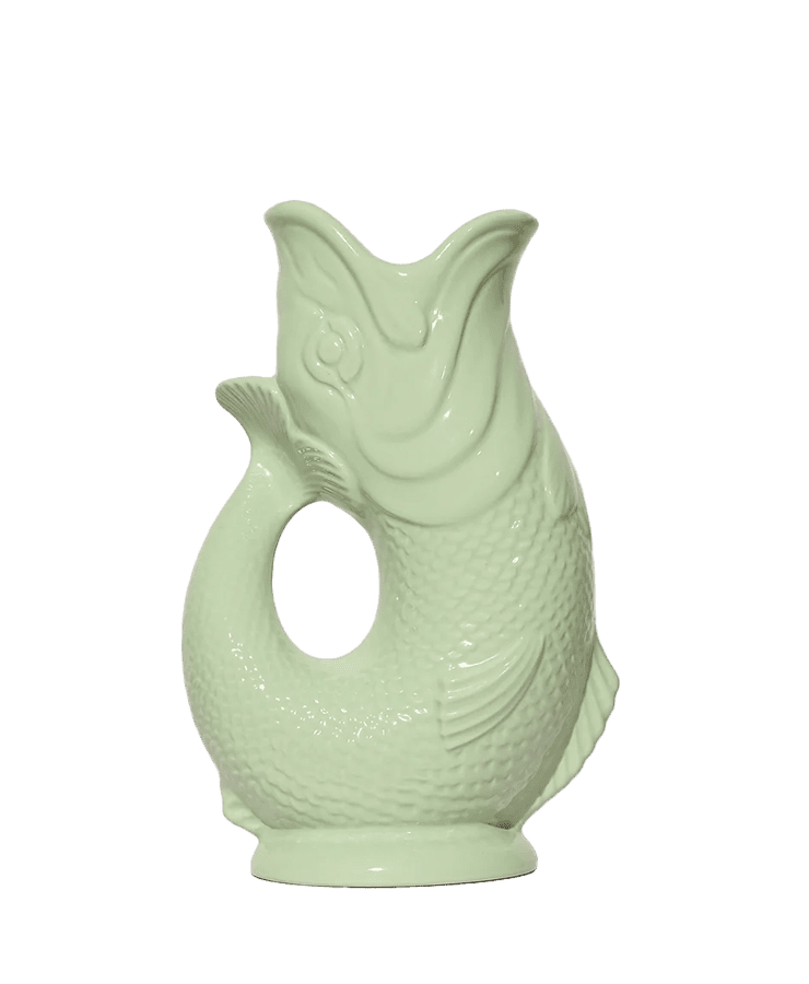 Der Gluckigluck Karaffe Large Pistazie Grün von Gluckigluck ist ein hellgrüner fischförmiger Keramikkrug mit strukturierten Schuppen und einem gebogenen Schwanzgriff, der vor einem schlichten weißen Hintergrund gezeigt wird.
