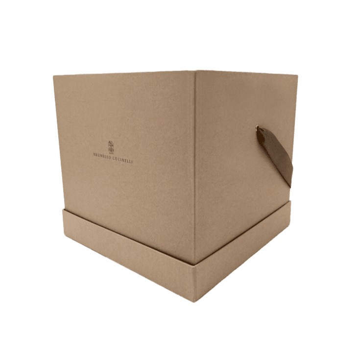 Eine große, quadratische, hellbraune Pappschachtel mit einer kleinen Stofflasche an der Seite und dem aufgedruckten Brunello Cucinelli-Logo auf der Vorderseite.