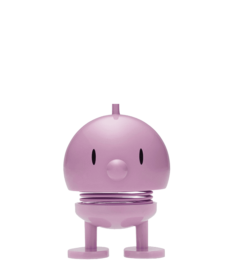 Der Hoptimist Bumble Medium Lavender von Hoptimist ist ein kleines, rundes, lila Spielzeug mit zwei ovalen Augen, einer knopfartigen Nase, einem optimistischen Lächeln und steht auf einer Metallfeder und flachen Füßen.