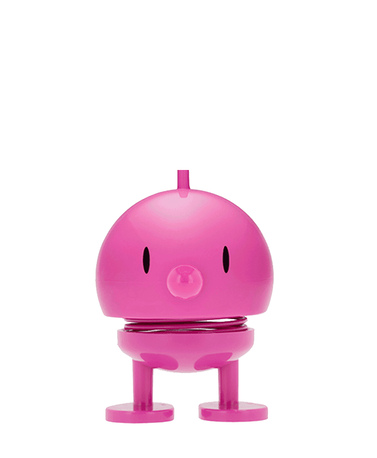 Der Hoptimist Bumble Medium Pink von Hoptimist ist eine kleine, runde Figur mit federnder Körpermitte, schlichtem Gesicht und zwei kurzen Beinen, die wie eine süße Zeichentrickfigur ein optimistisches Lächeln ausstrahlt.