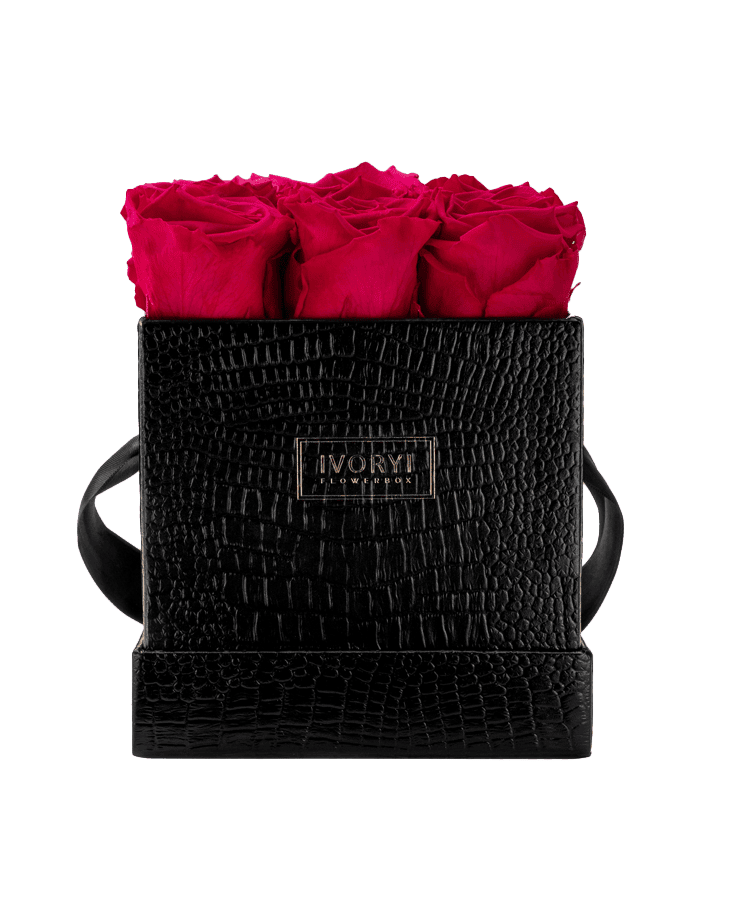 Die Ivoryi Flowerbox Medium Black New Pink von Ivoryi & Friends besteht aus einer schwarzen strukturierten Box mit Griffen, vier leuchtend rosa Rosen, einem goldenen IVORY-Etikett, ist handgefertigt in Deutschland und auf einem transparenten Hintergrund abgebildet.