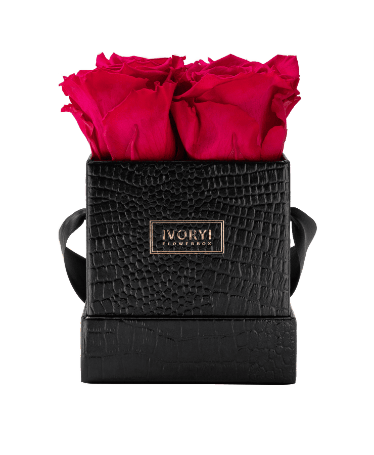 Die Ivoryi Flowerbox Small Black New Pink von Ivoryi & Friends ist eine kleine schwarze strukturierte Box mit einem goldenen Ivory Levu-Etikett, seitlichen Griffen und enthält drei leuchtende, langlebige Rosen in einem schicken, eleganten Design.
