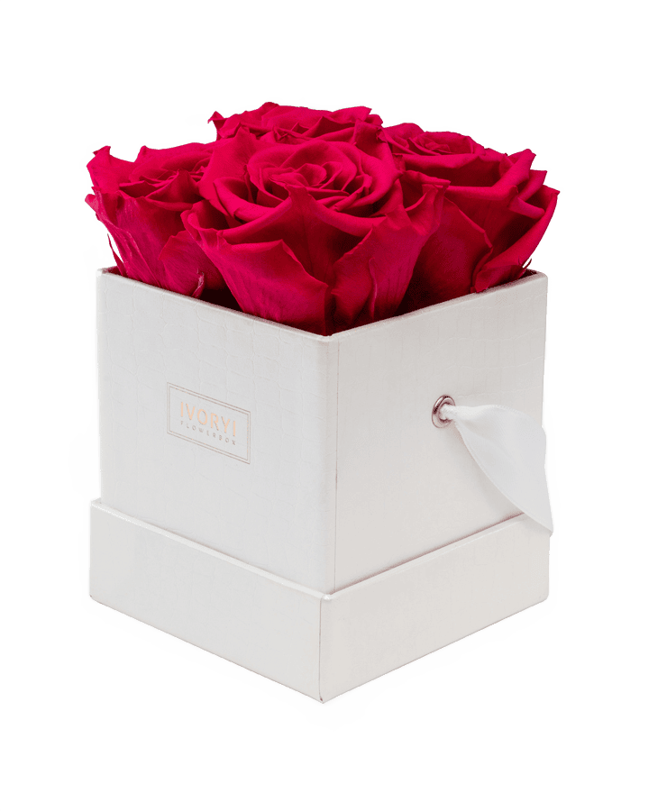 Die Ivoryi Flowerbox Small Perlmutt New Pink von Ivoryi & Friends verfügt über ein dezentes Strukturmuster, ein Etikett mit der Aufschrift „Ivory“ und enthält ordentlich angeordnete, leuchtend rote konservierte Rosen im Inneren, komplett mit einem Henkel aus Band.