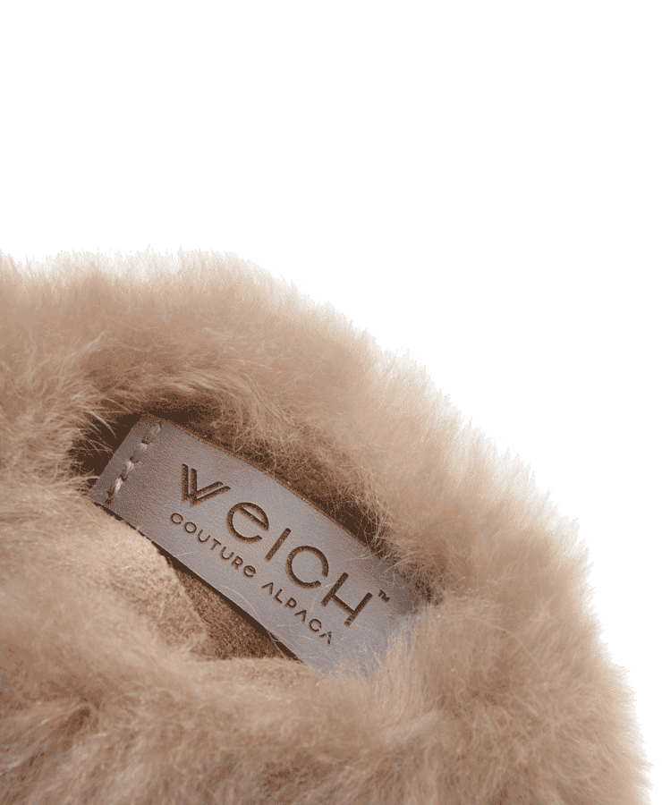 Nahaufnahme des weichen, flauschigen Taupe-Stoffes mit eingenähtem Weich Couture Alpaka-Etikett – das an königliches Alpaka-Vlies erinnert – gefertigt für die Alpaka Wärmflasche Regular Taupe.